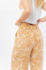Pantalón de corte culotte y tiro medio, confeccionado en viscosa con estampado de hojas blancas sobre fondo color miel. Presenta una silueta amplia y fluida, con cintura elástica en la parte posterior y bolsillos laterales.