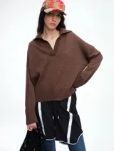 Sweater de punto color marrón, con cuello polo abierto en V, manga larga con hombro caído y terminaciones acanaladas.