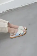 Sandalias planas color celeste y blanco, con tiras anchas cruzadas y suela color caramelo.