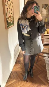 Camisa crop azul con estampado de motivos abstractos en blanco y rosa, cuello clásico y lazo en el escote.