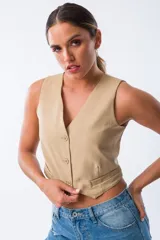 Chaleco color beige con escote en V y cierre frontal con tres botones.