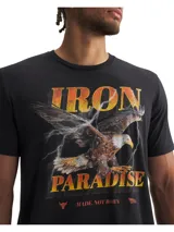 Remera de manga corta con cuello redondo acanalado, color negro. Presenta un estampado frontal con la frase 'IRON PARADISE', una imagen de un águila y rayos, junto con el texto 'MADE. NOT BORN'.
