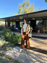 Cartera tipo bandolera de cuero color crudo, con diseño rectangular, solapa frontal con detalle de costura decorativa en el borde y correa ajustable.