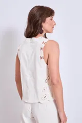 Blusa negra sin mangas, de corte recto y escote redondo, con detalles de bordados contrastantes en color blanco en los bordes y costados.