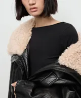 Remera negra de manga larga con cuello barco, confeccionada en tejido elástico y entallado.