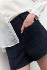 Short de tiro alto color azul marino, confeccionado en tejido tweed, con dos bolsillos frontales y cintura elástica.