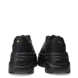 Championes Puma modelo Karmen X-TRA, de diseño urbano con plataforma elevada. Presentan un exterior sintético en color negro con detalles de textura, cordones al tono y ojales superiores metálicos dorados.