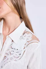 Vestido camisero corto color crudo, de lino, con cuello camisero, mangas largas y cierre frontal con botones. Presenta apliques de encaje en cuello y hombros.