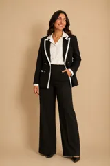 Blazer cruzado negro con vivos blancos en solapas y bolsillos, botones dorados frontales y en puños.