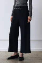 Pantalón culotte negro de tiro medio con trabillas y cinturón fino efecto piel con hebilla metálica. Presenta raya planchada y cierre de cremallera oculta en la costura.