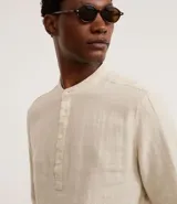 Camisa de manga larga confeccionada en mezcla de lino y algodón, con cuello tipo padre y cierre frontal parcial con botones. Presenta un corte amplio y cómodo, ideal para un estilo casual y fresco.
