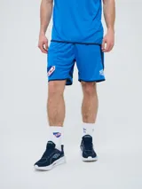 Short de entrenamiento Umbro del Club Nacional de Football, color azul con detalles en azul marino, escudo del club en una pierna y logo de la marca en la otra.