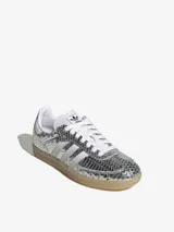Championes Adidas Samba LT con acabado metálico plateado y textura de piel de serpiente. Presenta las icónicas tres tiras blancas en los laterales, suela de goma color caramelo y cierre de cordones.