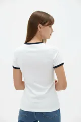 Remera de viscosa blanca con detalles en azul marino en el cuello redondo y los puños de las mangas cortas, de corte ajustado al cuerpo.