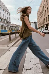 Top de punto color verde militar, con cuello subido y manga sisa. Presenta apliques dorados en los laterales y un bajo asimétrico.