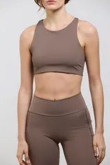 Top deportivo de compresión media con escote redondo, diseño al cuerpo y espalda abierta. Cuenta con elástico interno en la cintura para mayor sujeción.