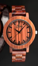 Reloj de pulsera con caja, esfera y malla de madera de sándalo rojo, con marcadores y manecillas negras. Presenta un diseño circular con corona lateral.