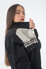 Campera de jean negra con detalles de cuero sintético plateado en la parte superior y tachas plateadas en los hombros.