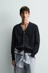 Cárdigan de punto relaxed fit confeccionado en mezcla de algodón y lino, en color azul marino. Presenta cuello en V, manga larga, bolsillos delanteros de plastrón, acabados en rib y cierre frontal con botones.