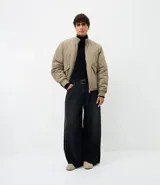 Campera bomber masculina de poliamida, con cuello, puños y ruedo de tejido elástico. Presenta cierre frontal con cremallera, dos bolsillos laterales con solapa y botón, y un pequeño bolsillo con cierre en una de las mangas.