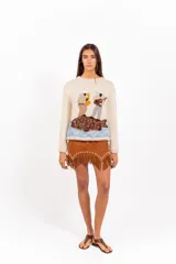 Sweater de punto color marfil, con cuello redondo, mangas largas y calce holgado. Presenta un bordado artesanal en el frente con diseño de dos músicos y un pez sobre fondo celeste.