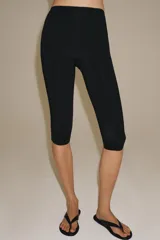 Pantalón capri negro de tiro medio y cintura elástica, confeccionado en hilatura con poliamida.