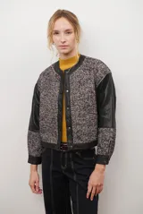 Chaqueta bomber color bordó con mangas de cuero sintético marrón y cuerpo de tweed con patrón de espiga. Cierre frontal con botones a presión y cuello redondo.