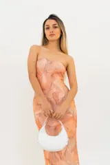 Vestido largo sin mangas, con escote palabra de honor y un estampado tipo batik en tonos naranjas y beige.
