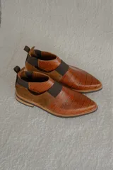 Zapato bajo de cuero color marrón con textura de cocodrilo, elástico lateral y tirador trasero.