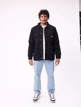 Campera de gabardina negra, con cuello camisero, cierre frontal de cremallera y botones a presión. Posee múltiples bolsillos frontales con solapa y puños ajustables con botones.