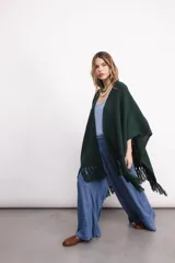 Ruana tejida en lana color verde oscuro, con textura de punto y terminación de flecos en los bordes.