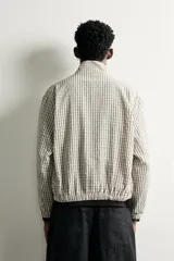Cazadora cropped fit para hombre con estampado a cuadros, cuello subido, cierre frontal con cremallera y bolsillos con solapa en la cadera.
