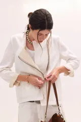 Chaqueta de lino lavado color blanco, con cuello mao, cierre metálico diagonal y detalles en contratono.
