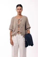 Saco de punto gris con frente abierto, cierre mediante lazos frontales y mangas con puños elásticos. Presenta una textura suave y un diseño de volumen holgado.