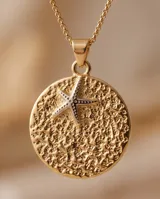 Collar de bronce con cadena fina y dije circular texturizado con una estrella de mar en el centro.