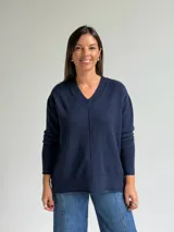 Sweater de punto en color azul marino, con escote en V, manga larga con puños acanalados y costura central vertical en el frente.