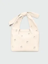 Bolso tote de cuero color marfil con perforaciones decorativas y bolsillo frontal con solapa. Asa de hombro con detalle de lazo. Modelo Le Pliage Broderié de Longchamp.