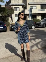 Minivestido de terciopelo azul con estampado geométrico en zig-zag en tonos celeste y azul marino. Presenta escote en V con ribete dorado y mangas 3/4 con puños dorados.