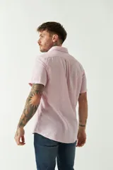 Camisa de manga corta confeccionada en una mezcla de lino y algodón, con cuello camisero, cierre frontal de botones y bolsillo en el pecho con logo bordado.