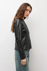 Chaqueta negra de cuero sintético, de manga larga, con detalle de pliegues en la parte frontal y cierre con cremallera.