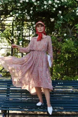 Vestido midi en gasa estampada con flores rojas sobre fondo beige, de manga al codo con volados en la falda y el cuello. Tiene cordón en la cintura para ajustar.