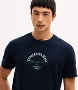 Remera de cuello redondo y manga corta, color azul marino, con estampa frontal tipo lettering con la leyenda Copacabana Beach.