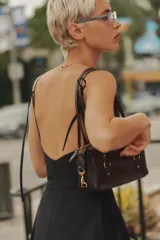 Vestido midi de gabardina en color negro, con cuello halter, tirantes finos y falda con vuelo. Cuenta con cierre en la espalda con cremallera oculta.