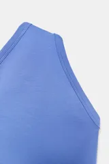 Body de tejido liso color azul claro, con escote asimétrico de un solo hombro y cierre inferior con broches a presión.