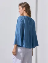 Blusa celeste de lyocell con cuello a la base y escote en V con lazo de ajuste. Manga larga amplia.