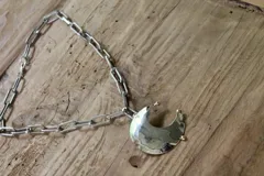 Collar plateado con cadena de eslabones grandes y dije de luna creciente texturizada. El dije está hecho de alpaca y bronce.