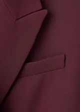 Americana de corte recto y diseño estructurado en color bordó. Presenta cuello con solapas de muesca, cierre frontal con botón, bolsillos laterales con solapa y un bolsillo de ribete en el pecho. Incluye forro interior completo y mangas largas.