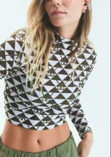 Polera de manga larga con cuello alto, confeccionada en lycra estampada con diseño geométrico de triángulos y monograma exclusivo de la marca.