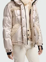 Campera de esquí Moncler modelo Mondium, de corte acolchado con acabado metalizado brillante. Presenta detalles de piel sintética en el pecho y bolsillos, capucha ajustable, cierre frontal con botones a presión y cinturón integrado con hebilla metálica con logo.