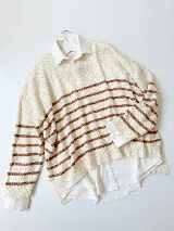 Sweater tejido color crema con rayas horizontales marrones, cuello redondo y corte holgado.